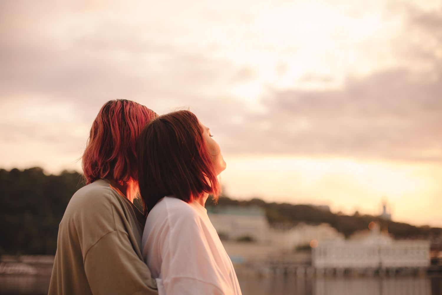Two people stand with their back to the camera watching the sunset