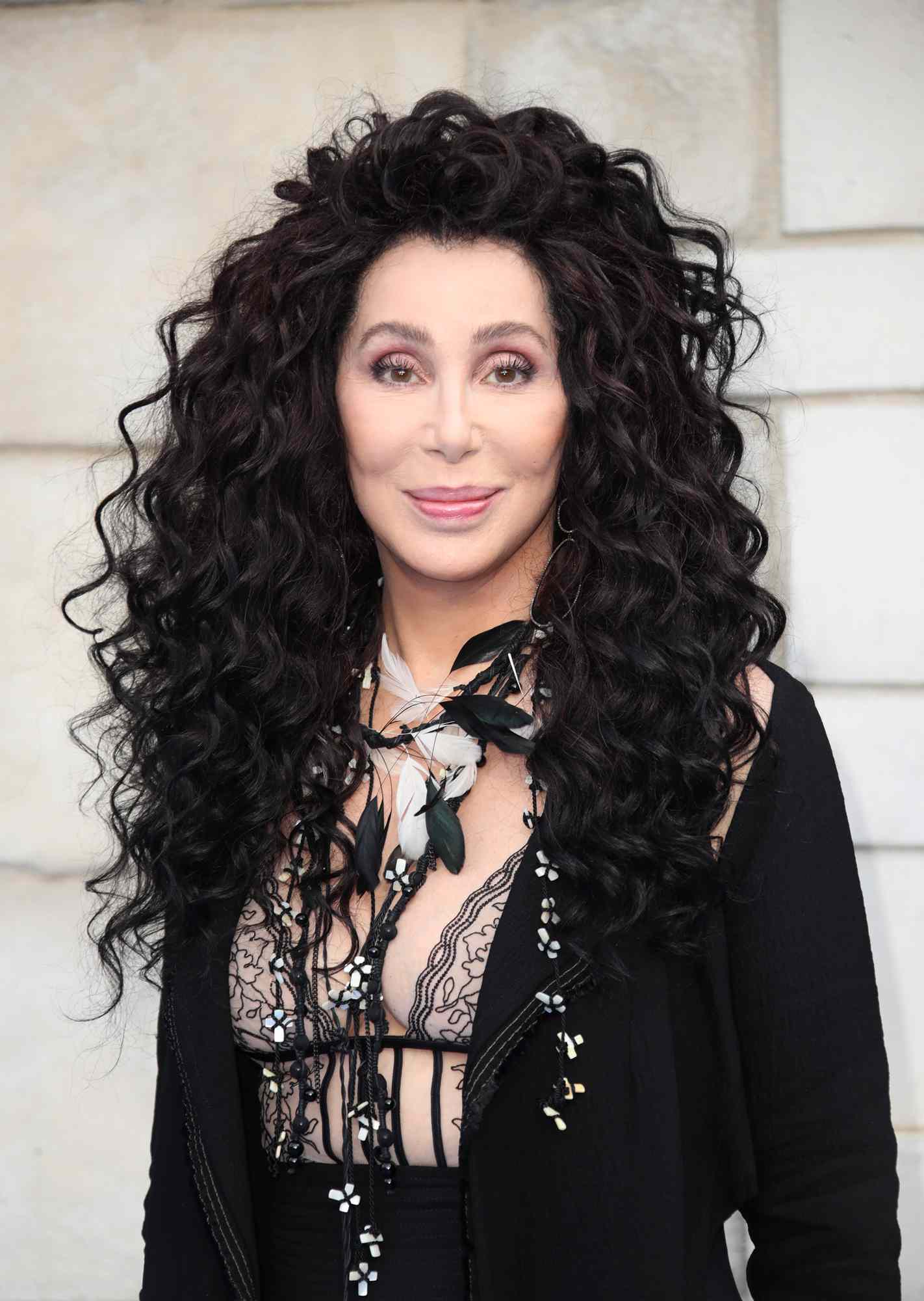 Cher wearing an all-black ensemble with a black lace bra