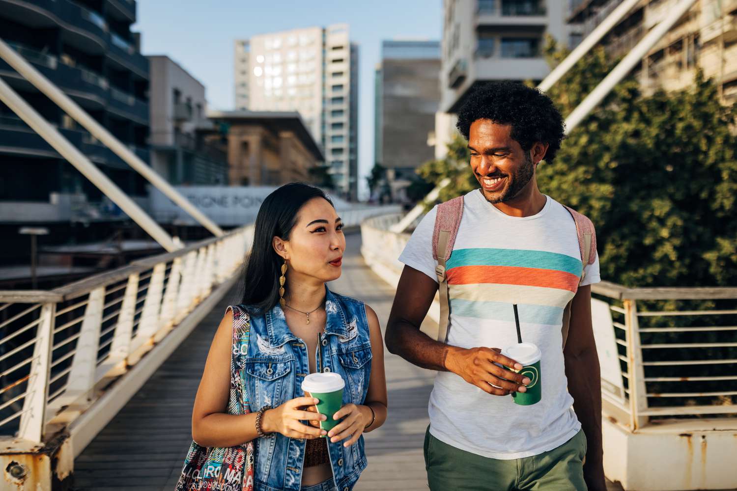 A woman and a man walk over a bridge in the sunshine