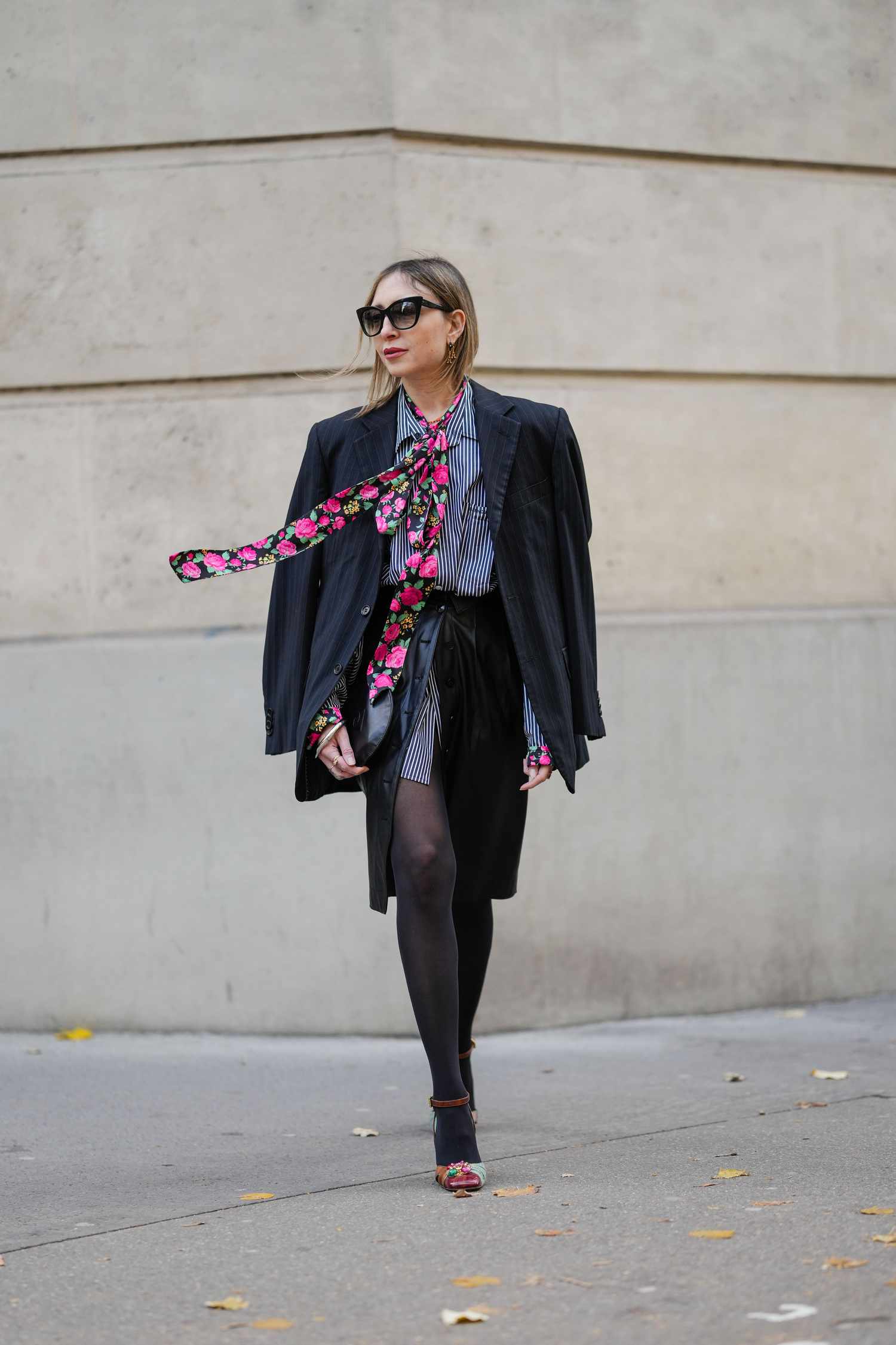 A woman wearing an oversized blazer, a skirt, and tights