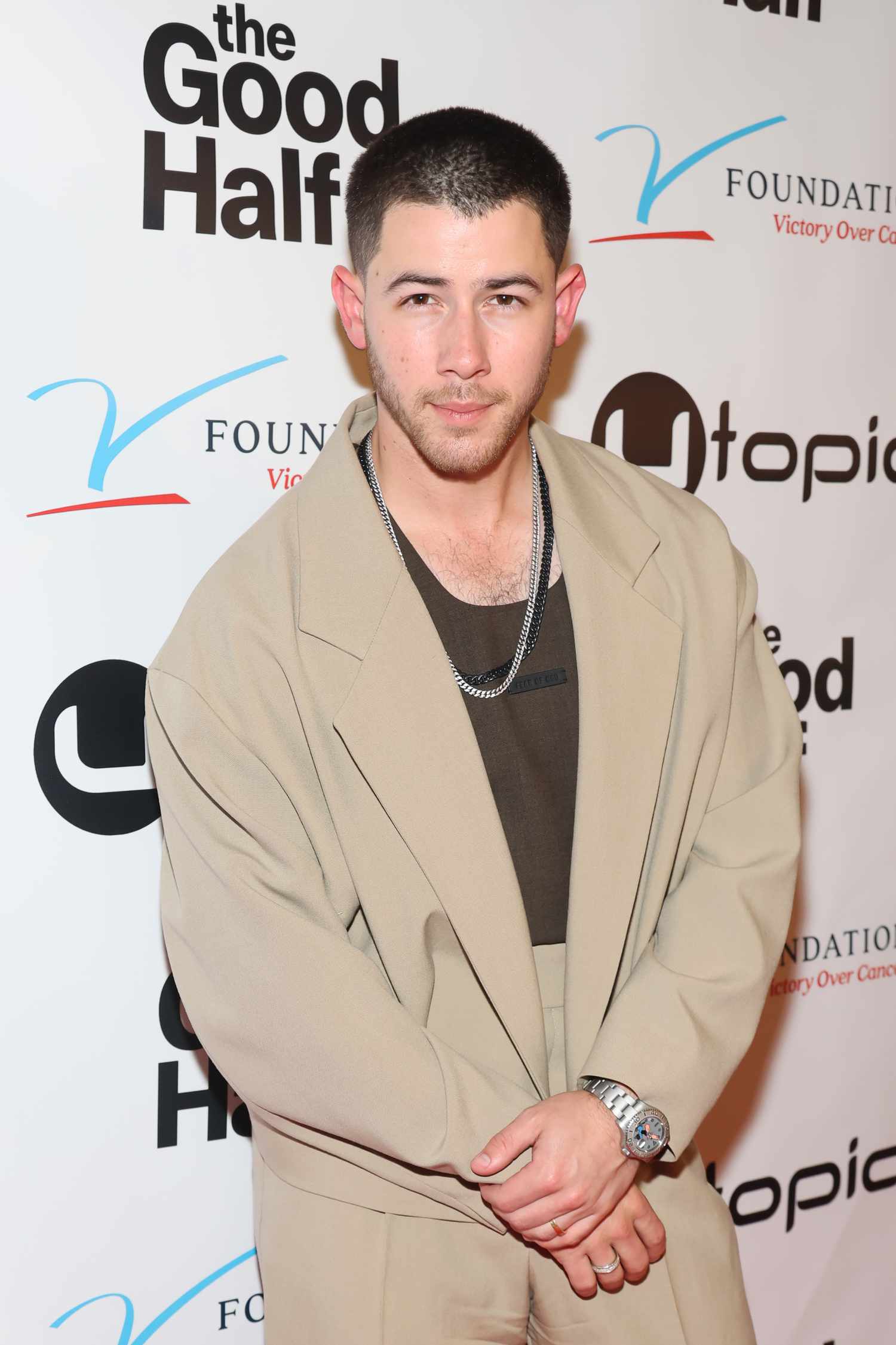 Nick Jonas wearing a beige suit with a green tank top in 2024