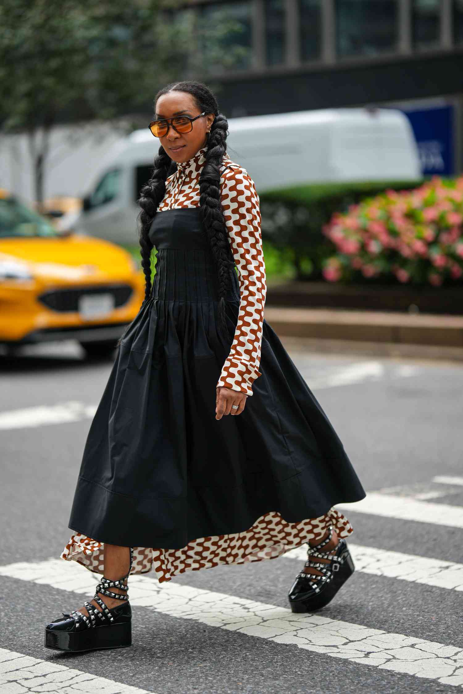 A woman wears a turtleneck printed dress under a black strapless dress, a 2023 Scorpio outfit for women to try.