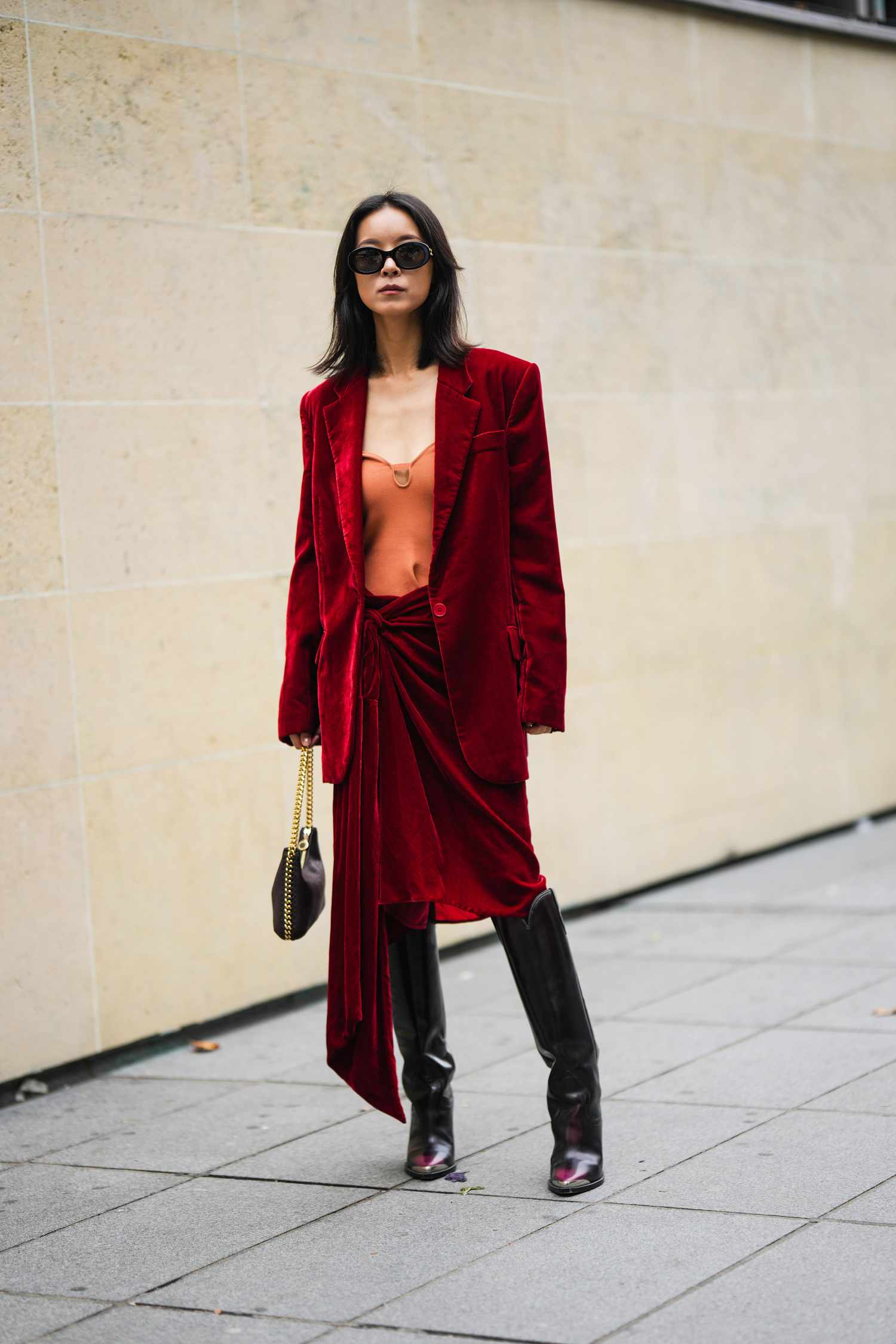 Person wearing a red velvet skirt suit with black knee-high boots