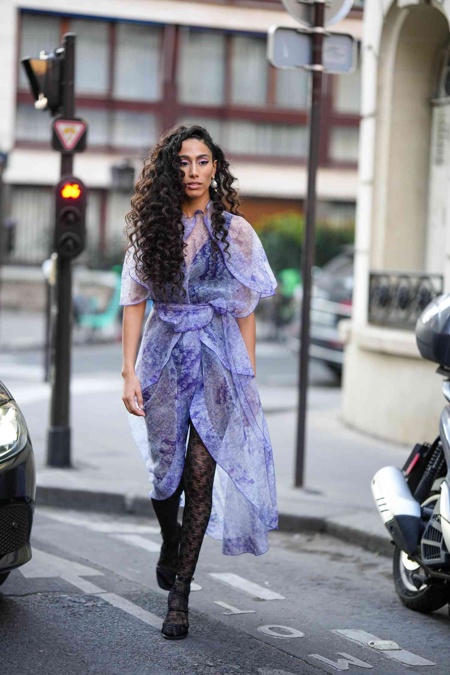 Person wearing a flowy purple sheer dress with black lace tights