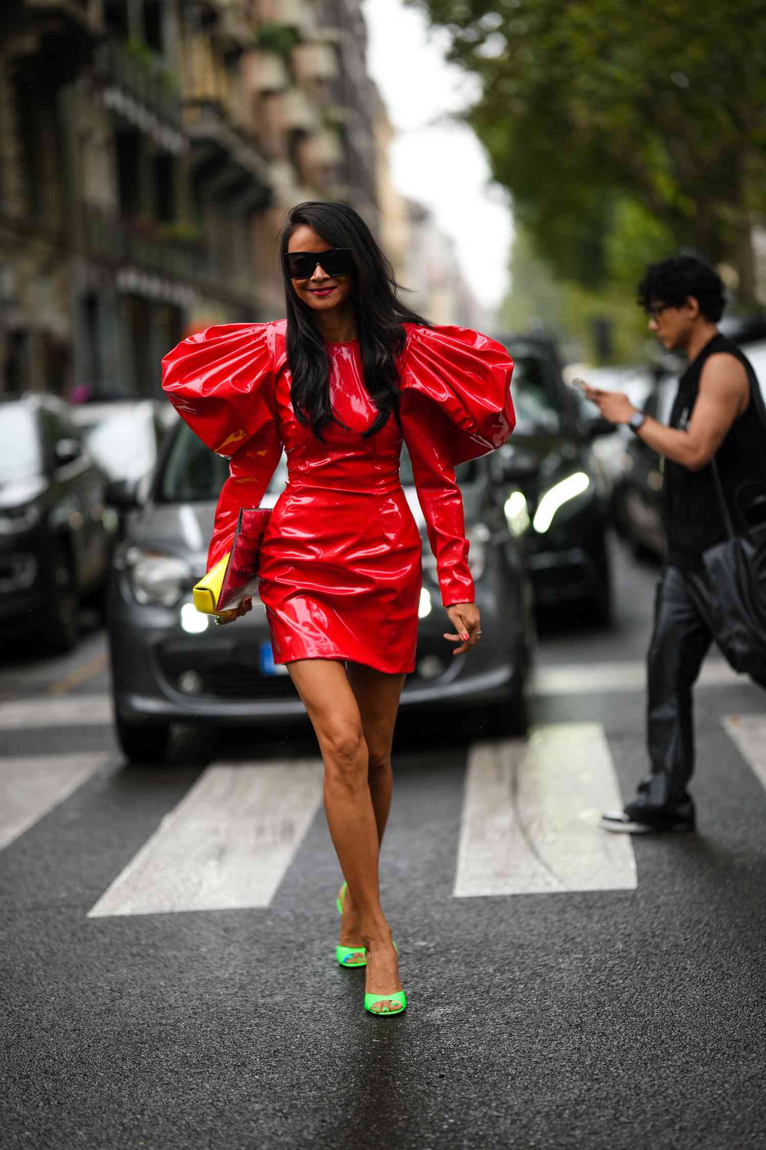 Person wearing a red latex dress with puff sleeves and neon green sandals