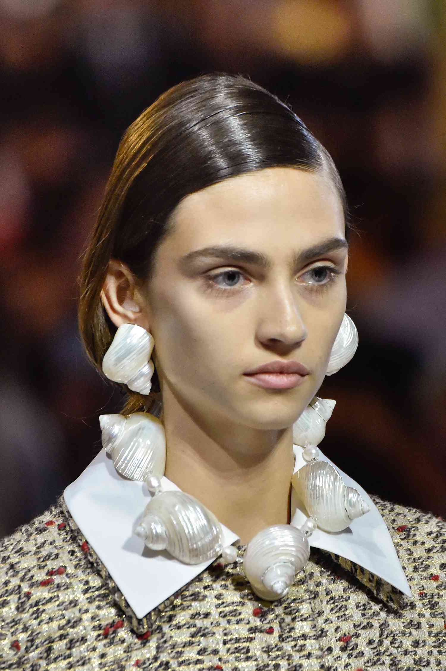 Showing Cancer fashion, Cancer Style, and how to dress like a Cancer zodiac sign, a model in a Prada runway show wears statement earring in the shape of seashells.