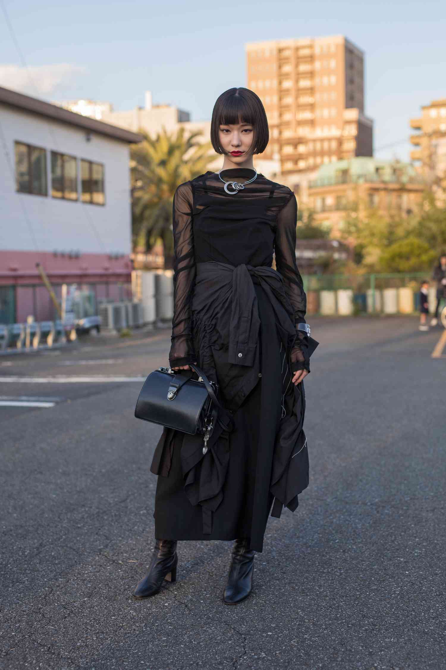 A woman wears a layered all-black outfit, a 2023 Scorpio outfit idea for women.