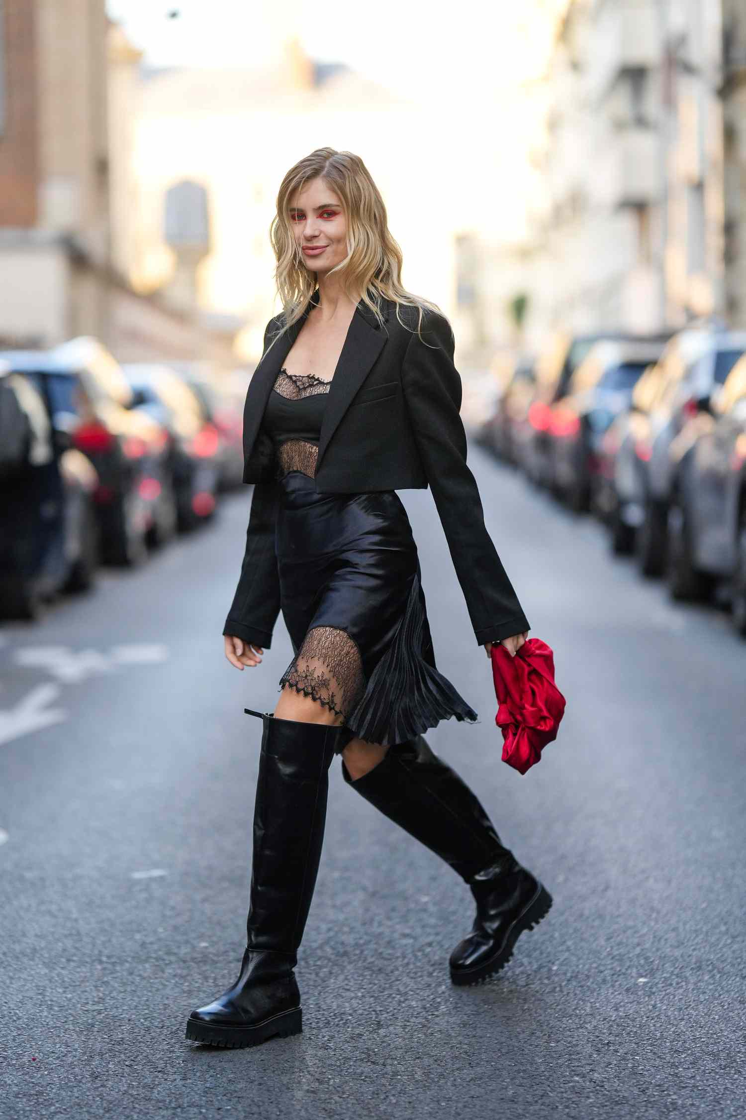 Xenia Adonts wears a black slip dress with a red bag and boots, a 2023 Scorpio outfit for women.