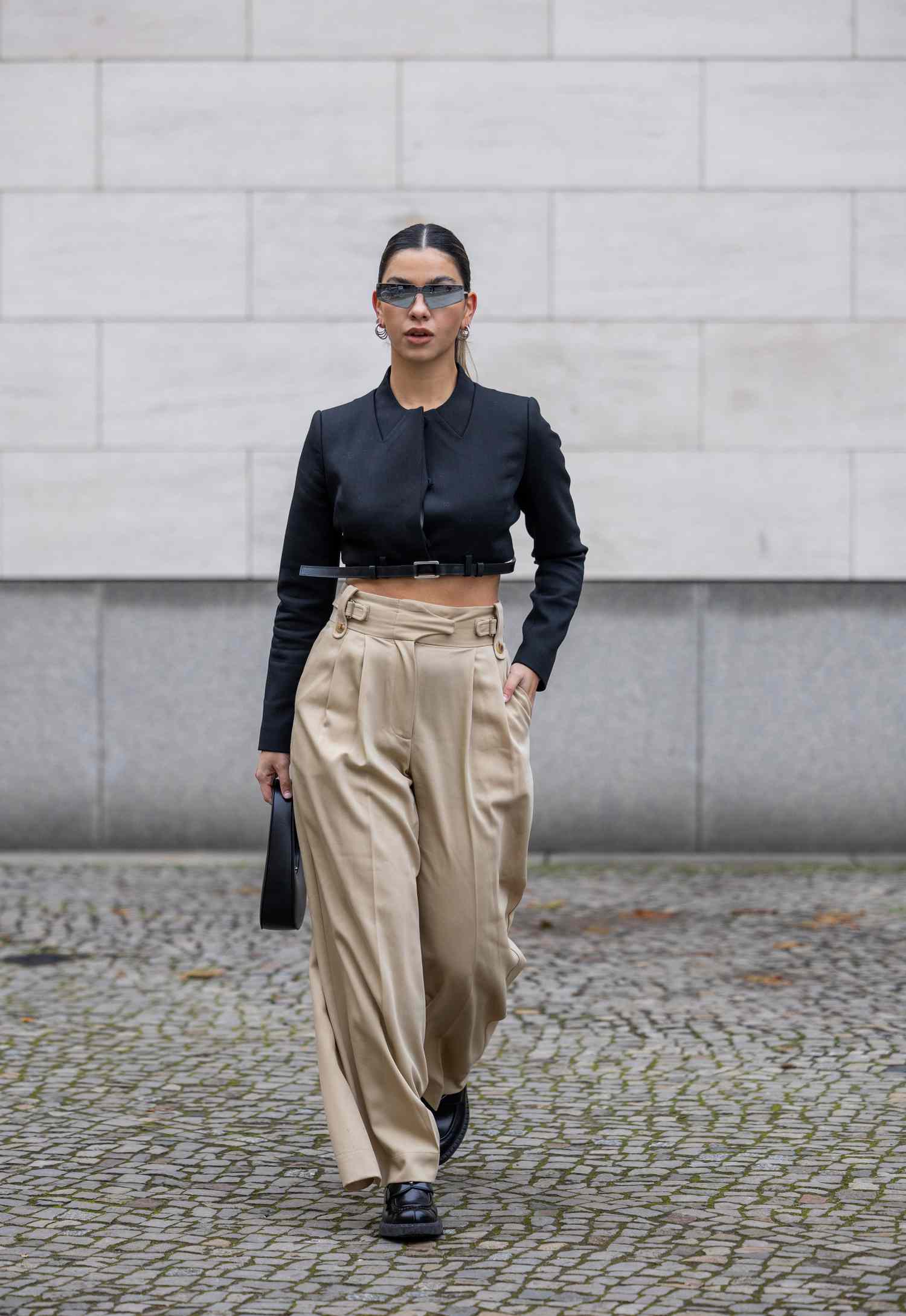 Person wearing a cropped black jacket and high-waisted beige trousers