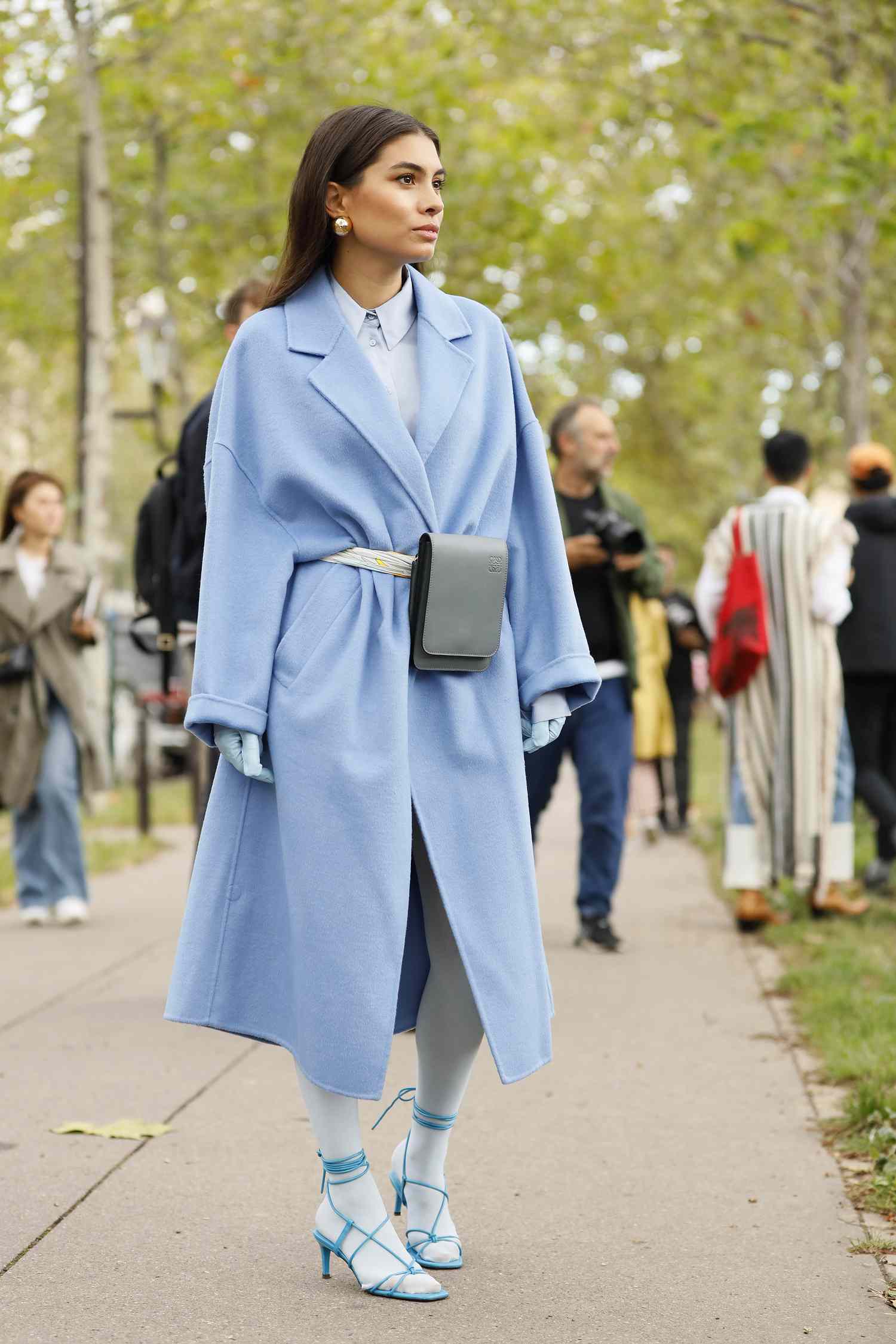 A woman wears a pale blue coat and pale blue gloves, a Libra outfit to try for 2023.