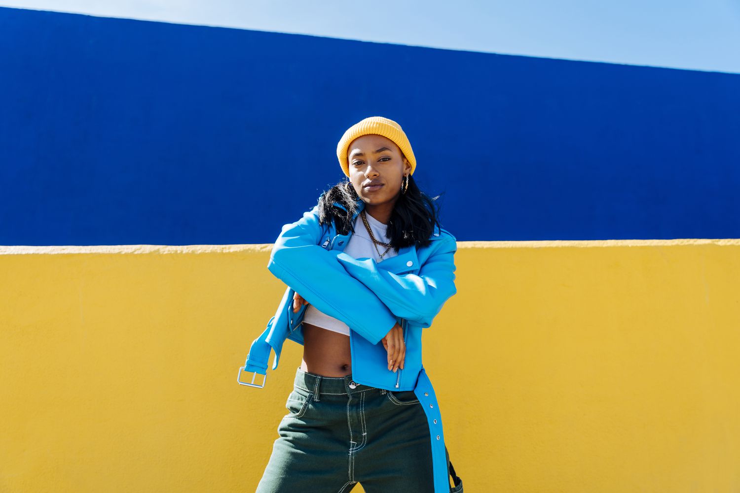 A woman wearing a blue jacket with a yellow beanie and green pants