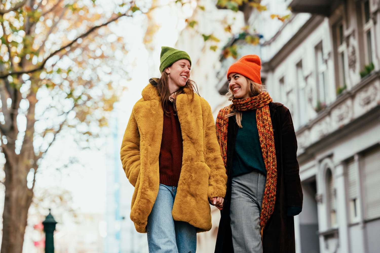 Two women walk and smile wearing winter coats and beanies
