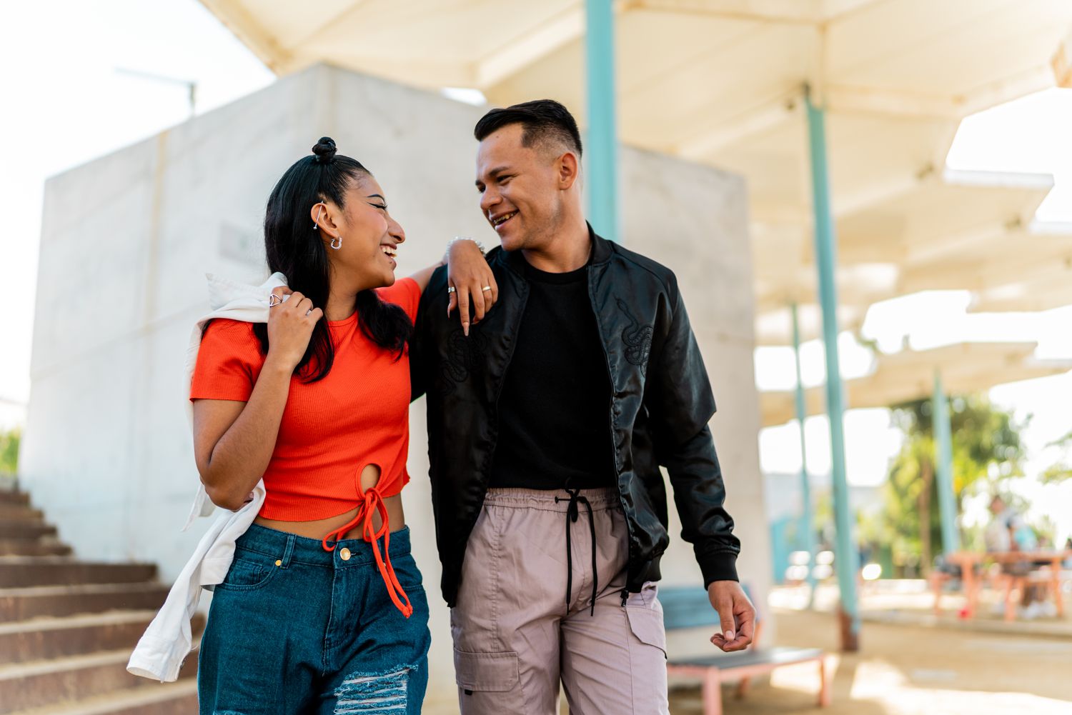 Two people walking down the street with their arms around each other, smiling