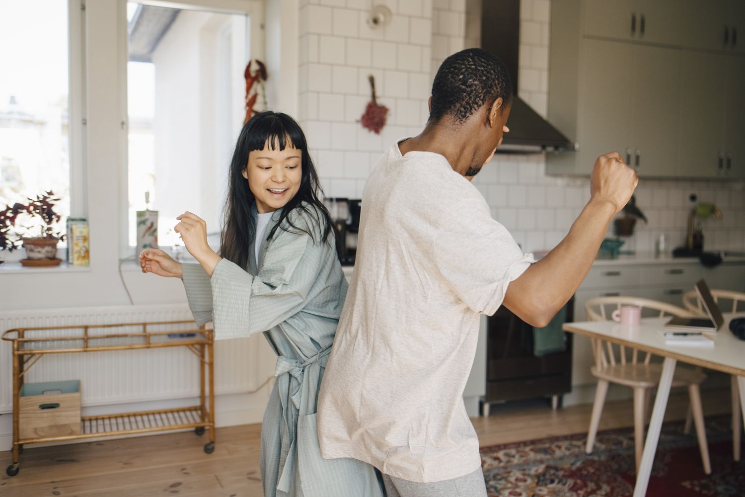 Two people dancing and bumping hips in a kitchen