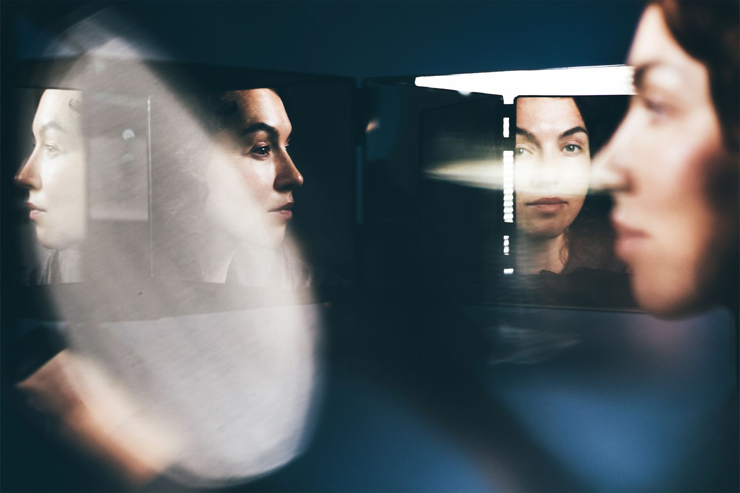 A person shown reflected multiple times in mirrors, creating an artistic composition