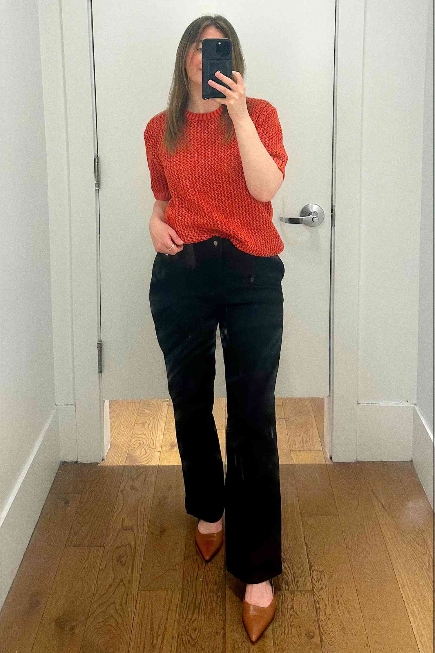 Person taking a mirror selfie while wearing a red top and dark pants