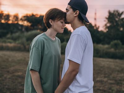 A couple stands in a field at sunset