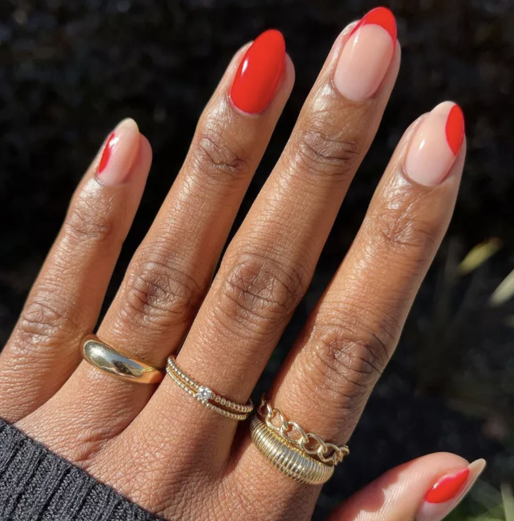 Hand with red and nude polished nails wearing gold rings