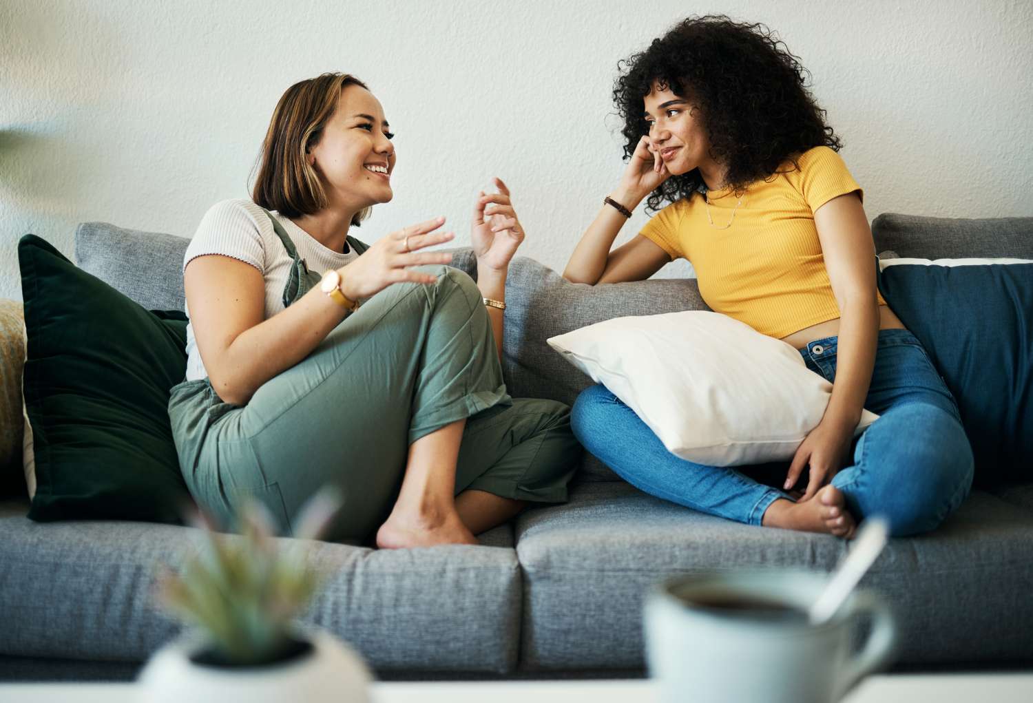 Two women sitting on a couch engaged in conversation, with one leaning forward gesturing