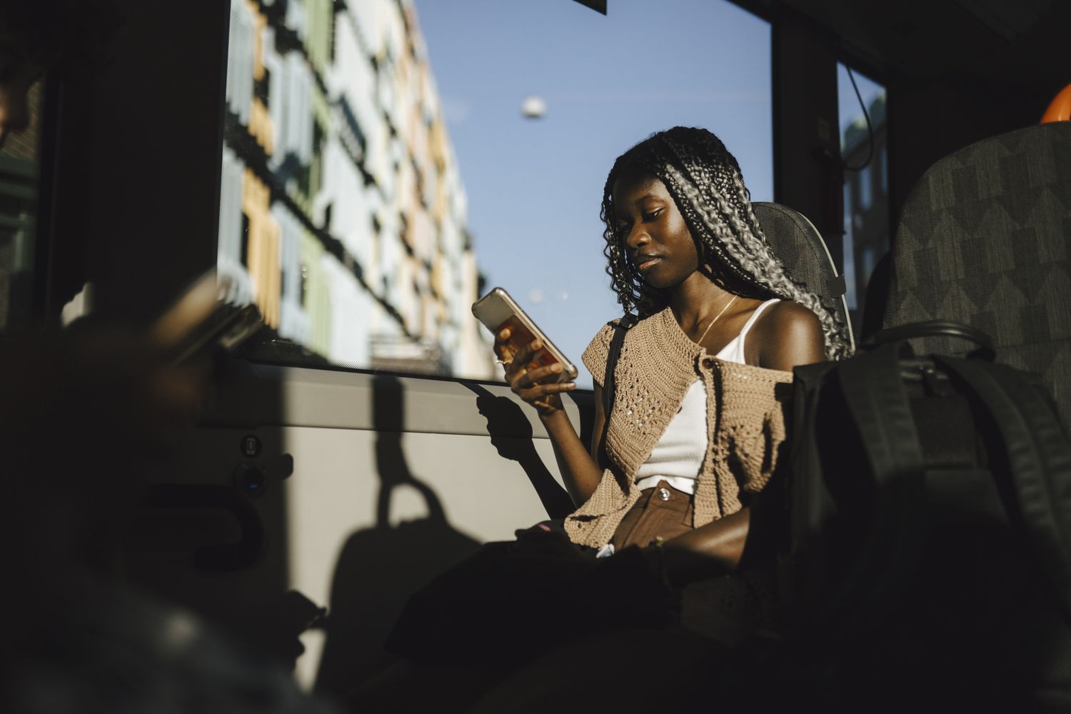 A person sitting on a bus looking at their smartphone
