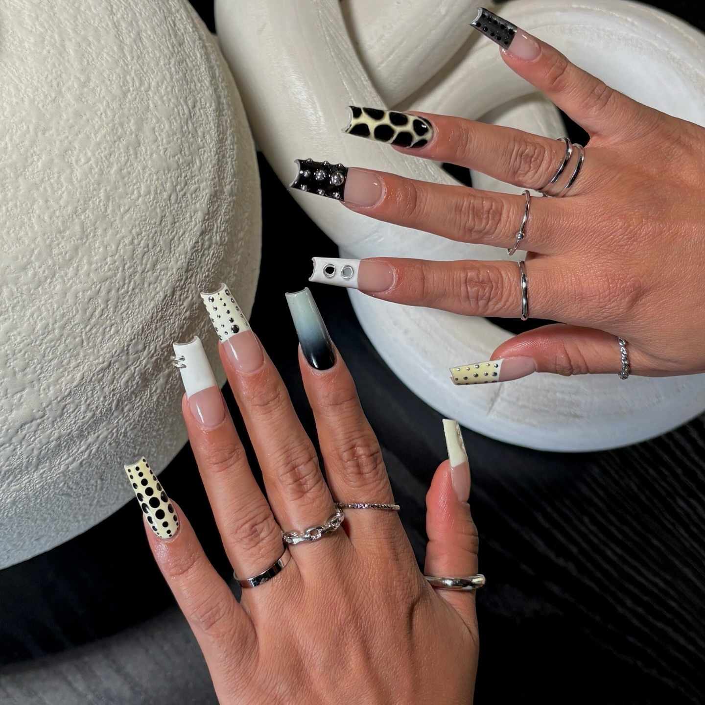 Close-up of hands with rings and decorated nails.