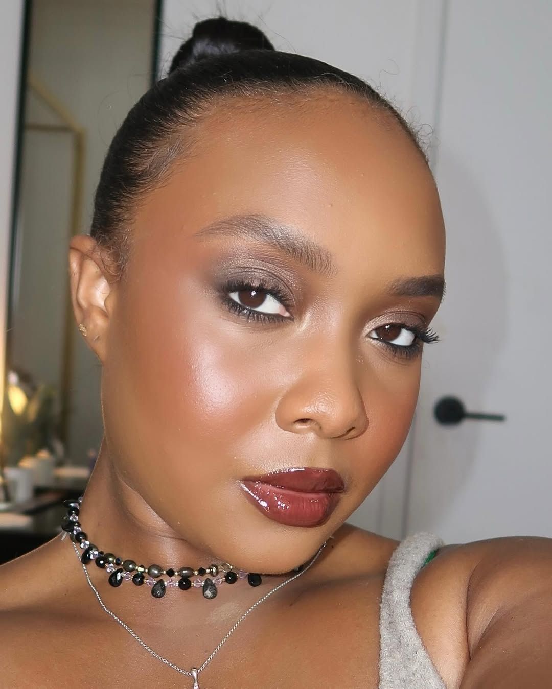 A person with smokey eye shadow, red lipstick and a black beaded choker