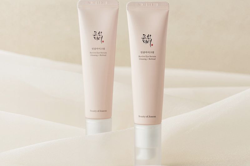 Two tubes of skincare product displayed on a soft fabric background