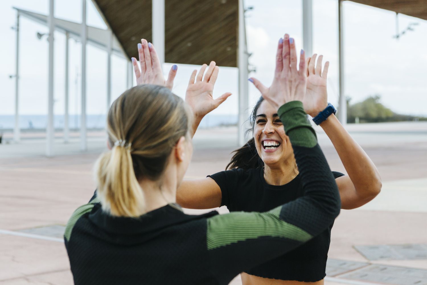 Two women doing a highfive outdoors while exercising together