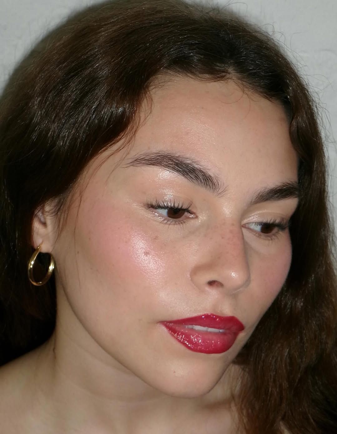 Close up of a person with dark wavy hair and bright red lipstick