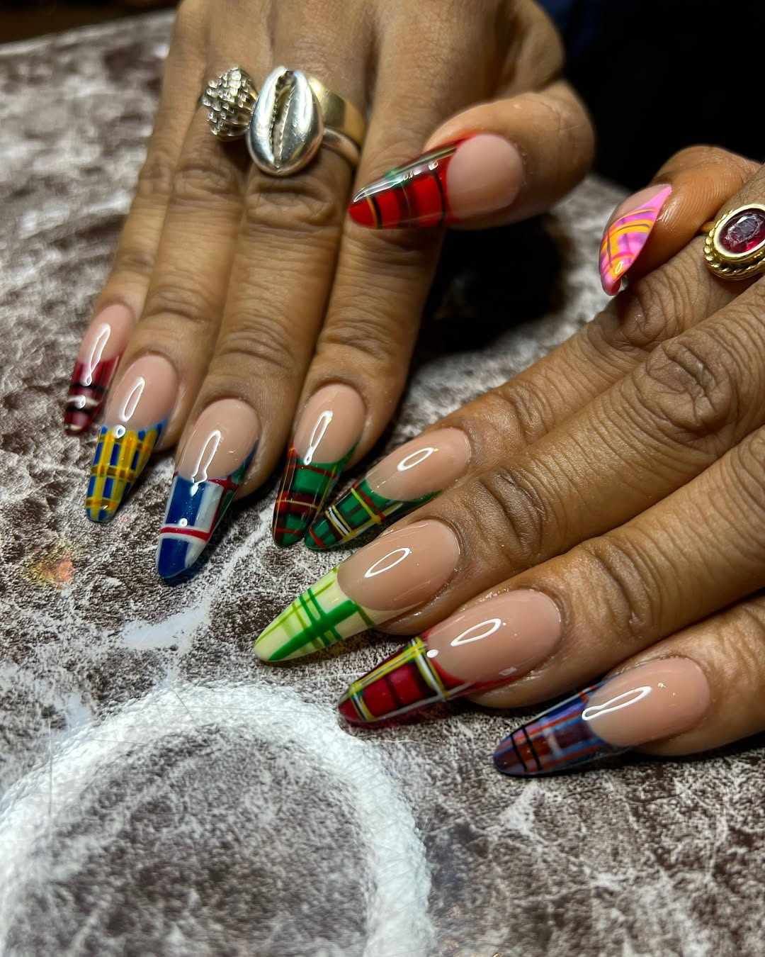 Hands with long nails painted with colorful plaid patterns