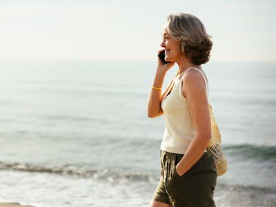 A person walking on a beach while talking on a phone