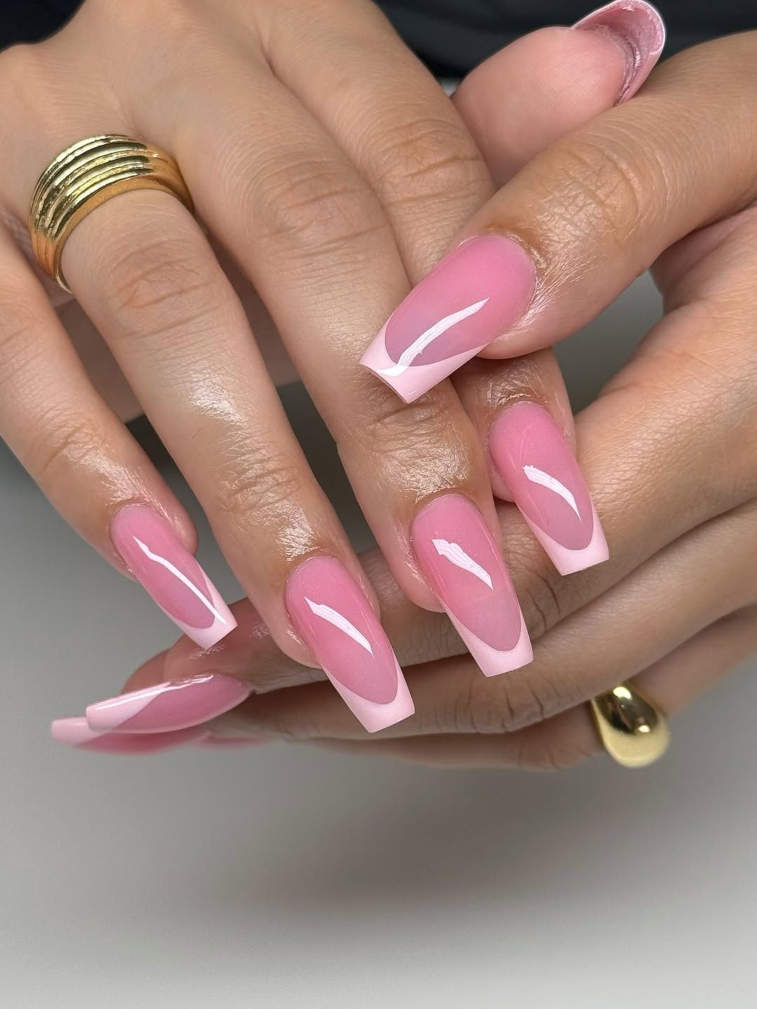 Close up of hands with a long, square, pink manicure