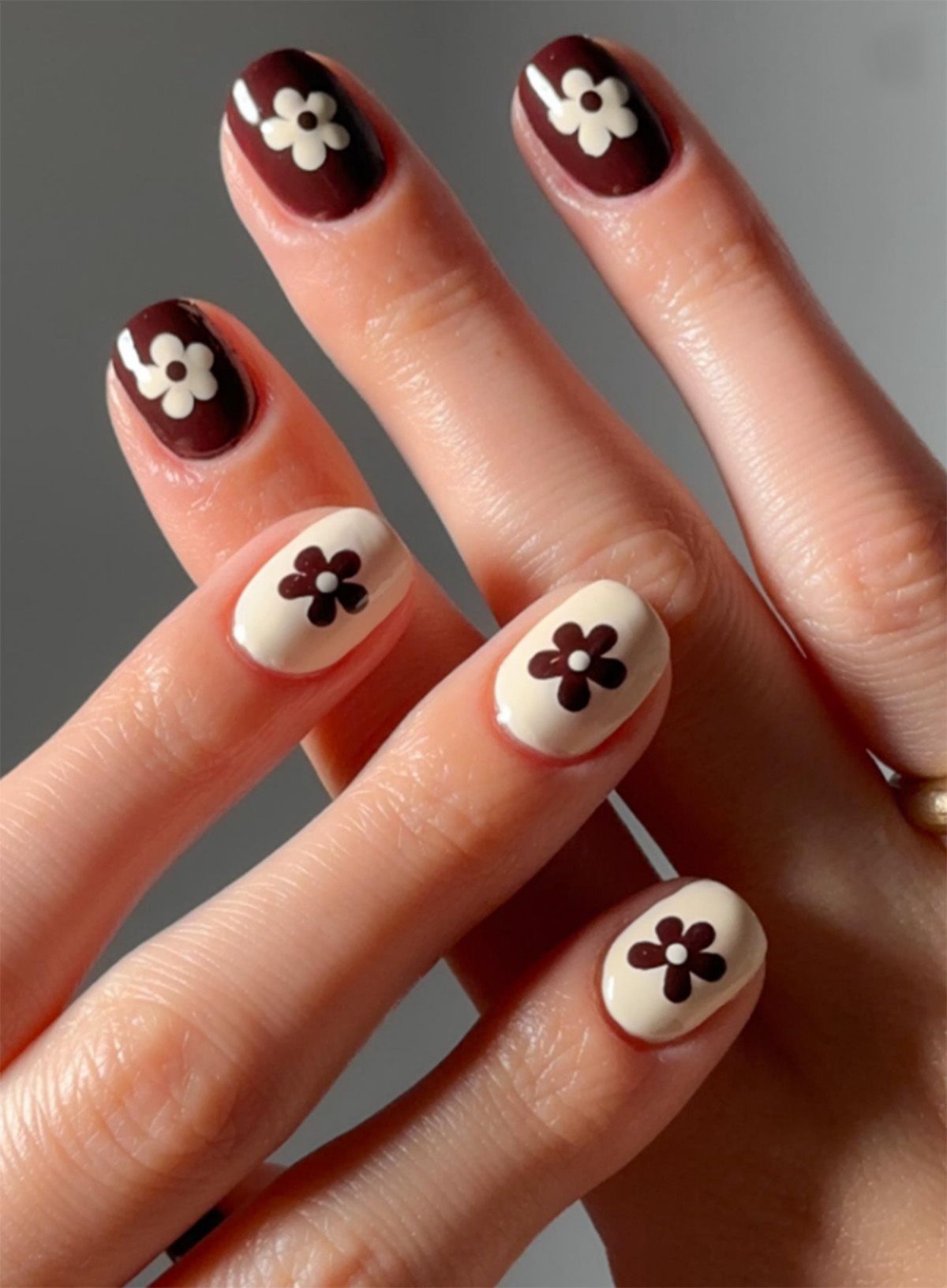 Hands displaying floral nail art with contrasting colors