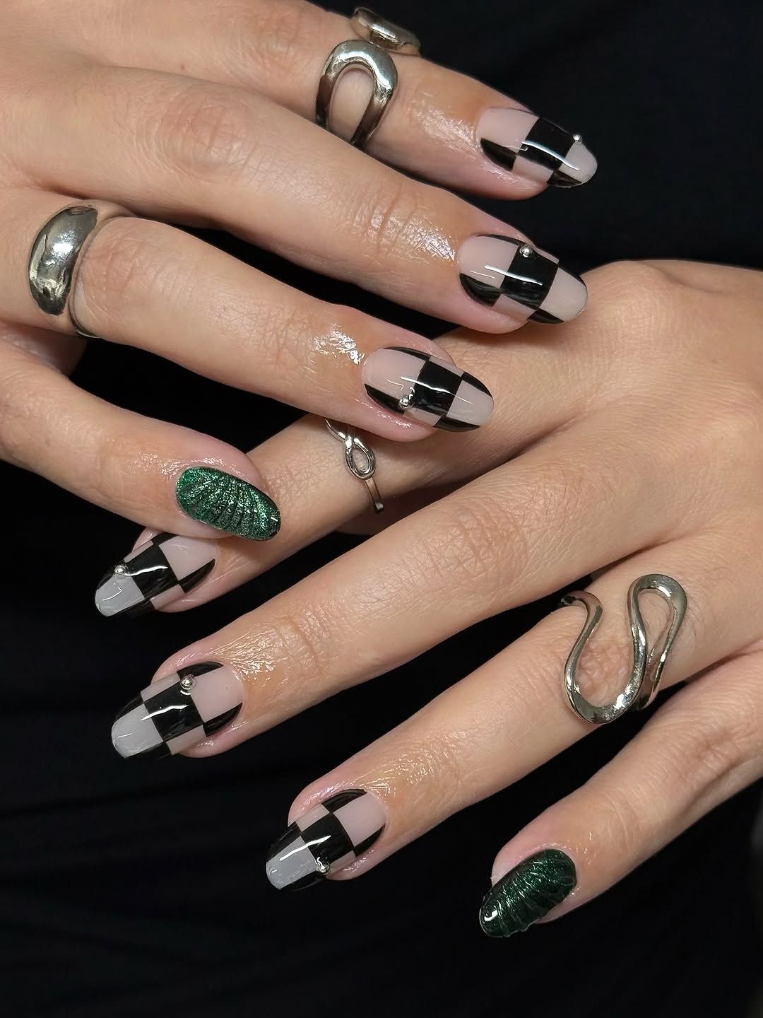 Hands showcasing detailed fingernail art with geometric patterns and metallic rings