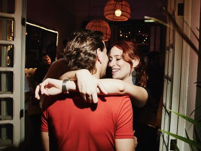 A couple embraces in the doorway at a party