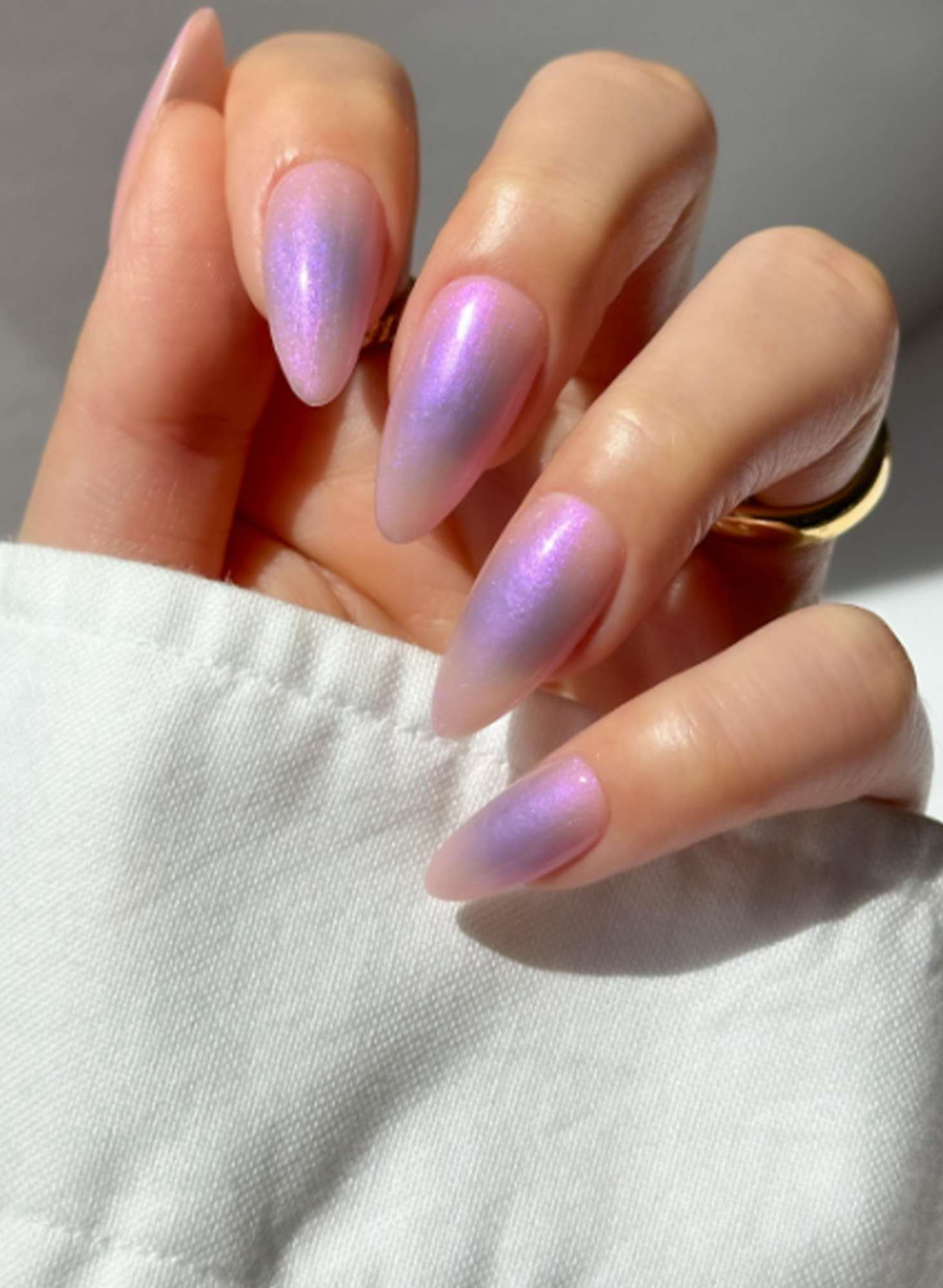 A hand with manicured nails featuring a shiny gradient finish