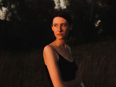 Woman outside looking off the side while cast in sunset lighting