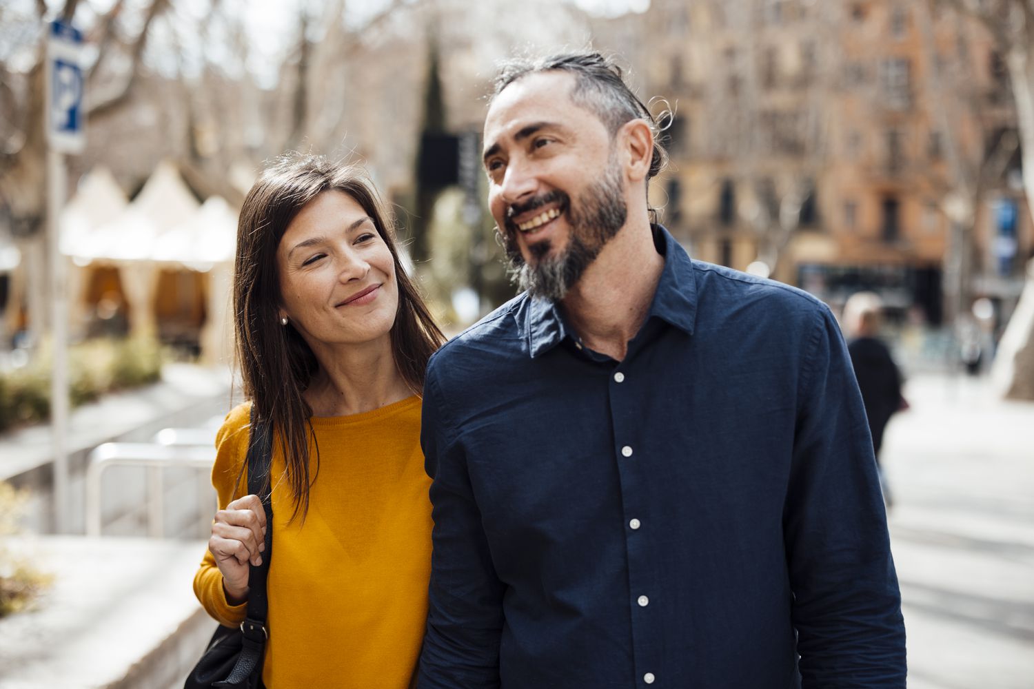 A smiling couple walks outside in the sun