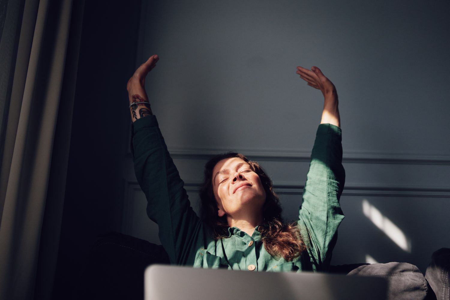 A person sitting and stretching their arms upward appearing relaxed