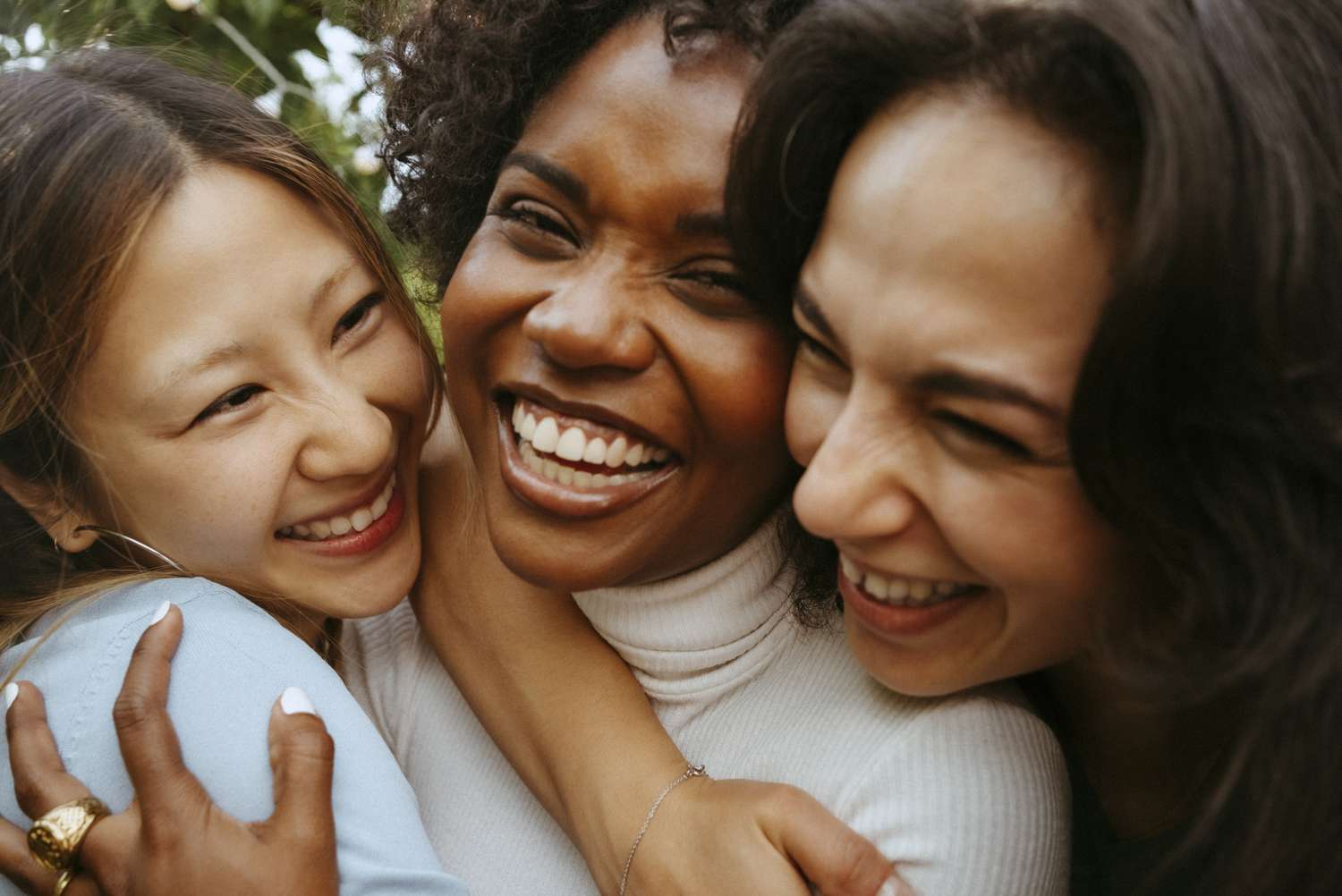 Three individuals close together smiling and laughing