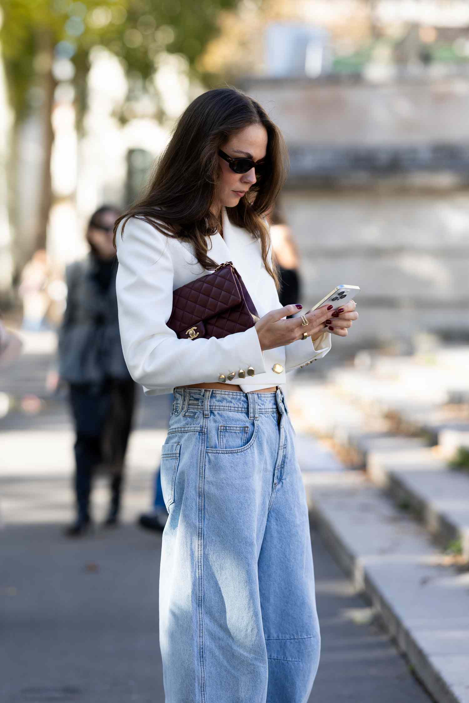 Person wearing sunglasses and holding a smartphone in an outdoor setting