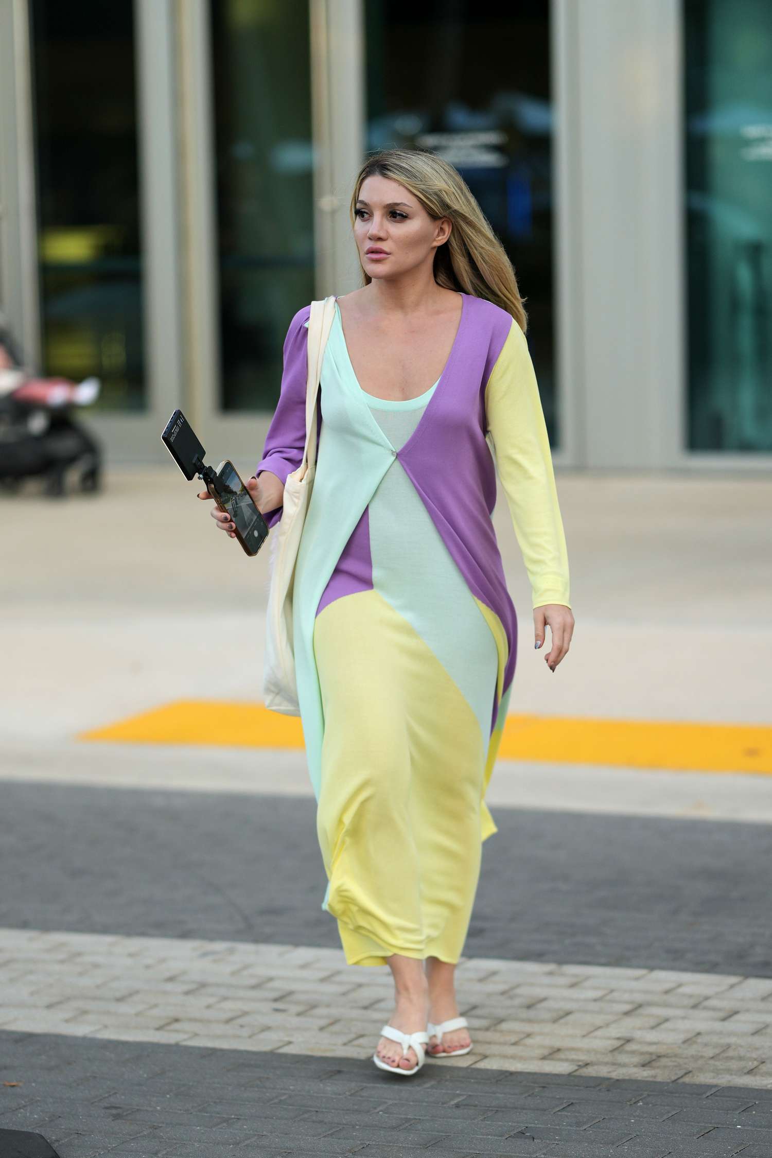 A woman walking outdoors holding an object resembling a camera